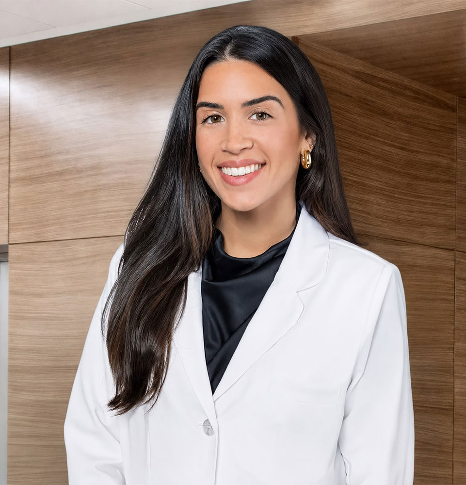 Dr. Stephany Ferreira, prosthodontist at Pleasant Valley Dentistry, smiling in a white coat.